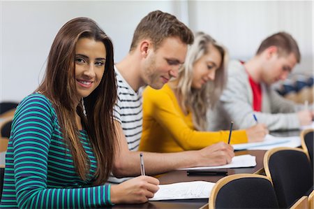 simsearch:6109-07497587,k - Happy brunette student looking at camera in classroom in a college Foto de stock - Sin royalties Premium, Código: 6109-07497549