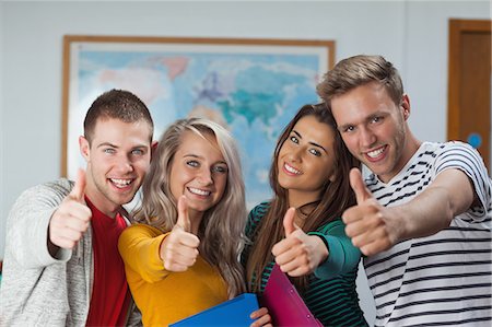 simsearch:6109-07497575,k - Cheerful casual students showing thumbs up in hallway in a college Foto de stock - Sin royalties Premium, Código: 6109-07497565