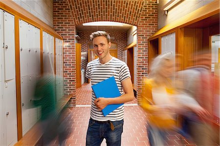 Smiling handsome student standing in hallway at college Stock Photo - Premium Royalty-Free, Code: 6109-07497573