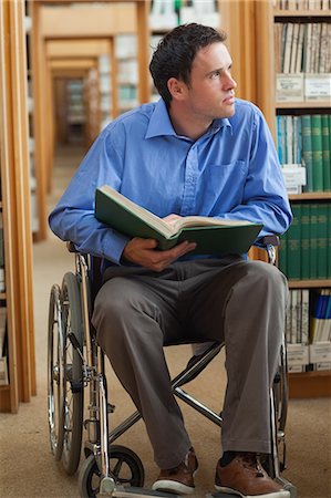 simsearch:6109-07497503,k - Thoughtful man in wheelchair holding a book in library in a college Stock Photo - Premium Royalty-Free, Code: 6109-07497501