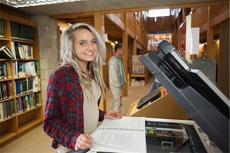 simsearch:6109-07497515,k - Cheerful blonde student standing next to photocopier in library in a college Photographie de stock - Premium Libres de Droits, Code: 6109-07497516