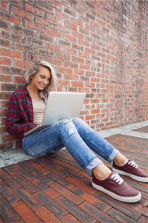 simsearch:6109-07497517,k - Lucky gorgeous student leaning against wall using laptop on college campus Foto de stock - Royalty Free Premium, Número: 6109-07497520