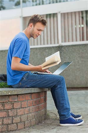 simsearch:6109-07497517,k - Content handsome student sitting on wall studying on college campus Foto de stock - Royalty Free Premium, Número: 6109-07497526