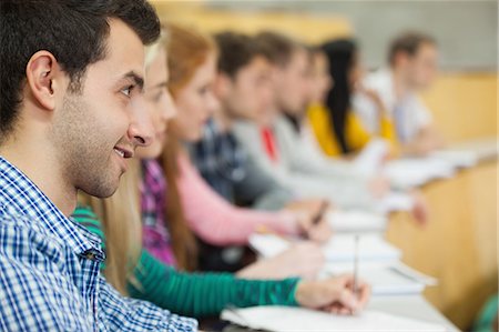 simsearch:6109-07497607,k - Row of smiling students listening in a lecture hall in college Foto de stock - Sin royalties Premium, Código: 6109-07497654