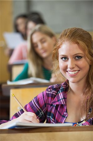 studying - Smiling red head student taking notes in a lecture hall in college Stock Photo - Premium Royalty-Free, Code: 6109-07497661
