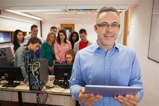 Computer teacher standing in front of his class using a tablet in college Photographie de stock - Premium Libres de Droits, Le code de l’image : 6109-07497680