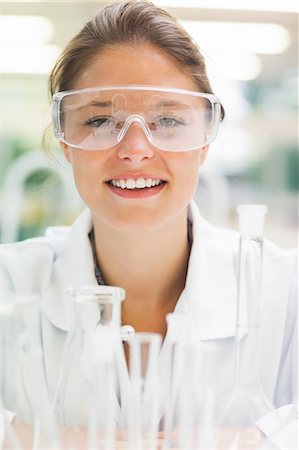 safety glasses - Smiling student wearing safety glasses in front of test tubes in lab at college Photographie de stock - Premium Libres de Droits, Code: 6109-07497789