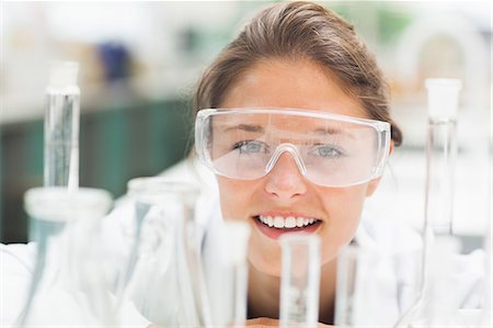 simsearch:6109-07497797,k - Cheerful student wearing safety glasses in front of test tubes in lab at college Fotografie stock - Premium Royalty-Free, Codice: 6109-07497790