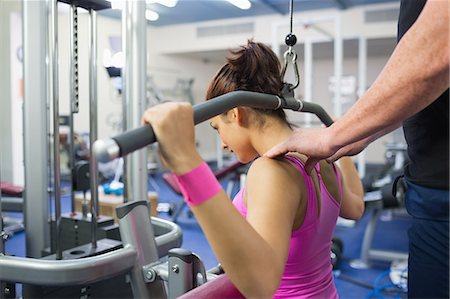 simsearch:6109-07497933,k - Instructor correcting shoulder position of woman of working out in weights room of gym Fotografie stock - Premium Royalty-Free, Codice: 6109-07497850