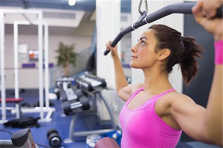 simsearch:6109-07497869,k - Calm brunette exercising on weight machine in weights room of gym Foto de stock - Sin royalties Premium, Código: 6109-07497874