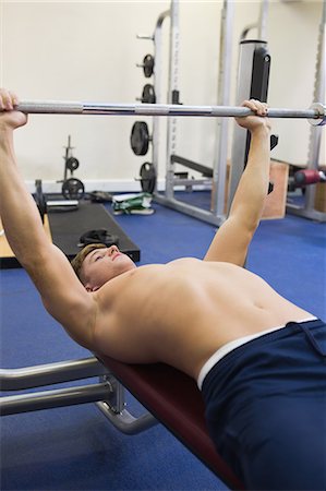 simsearch:6109-07497902,k - Muscular man lying on bench lifting barbell in weights room of gym Photographie de stock - Premium Libres de Droits, Code: 6109-07497893