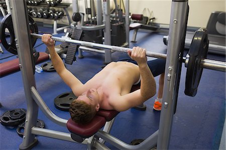 simsearch:6109-07497902,k - Handsome man lying on bench lifting barbell in weights room of gym Photographie de stock - Premium Libres de Droits, Code: 6109-07497897
