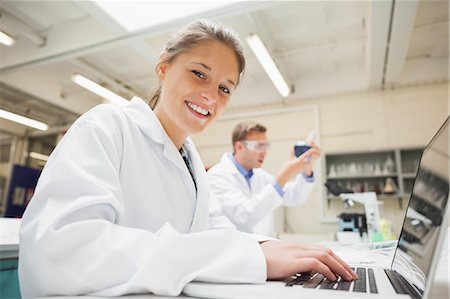research - Cheerful student working at laptop and looking at camera in lab at college Stock Photo - Premium Royalty-Free, Code: 6109-07497821