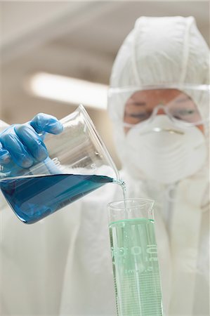 simsearch:6109-07497806,k - Lab assistant with mask pouring blue liquid in beaker in lab at college Fotografie stock - Premium Royalty-Free, Codice: 6109-07497827