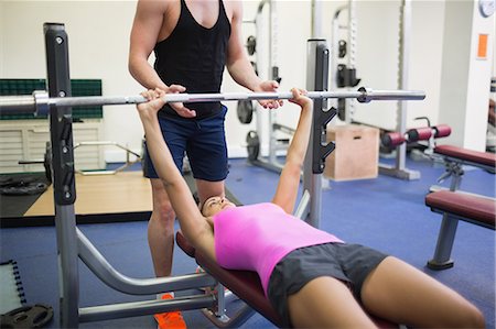 simsearch:6109-07497869,k - Trainer helping lying woman exercising with barbell in weights room of gym Foto de stock - Sin royalties Premium, Código: 6109-07497835