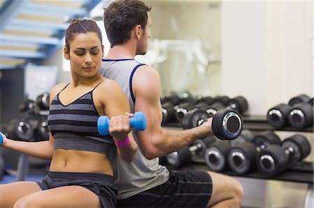 simsearch:6109-07497947,k - Woman and man lifting dumbbells in weights room of gym Foto de stock - Sin royalties Premium, Código: 6109-07497940