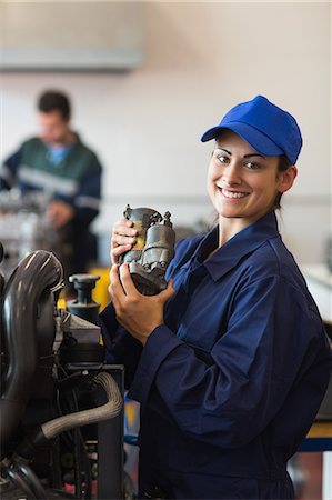 simsearch:6109-07497961,k - Cheerful trainee showing part of a machine in workshop Photographie de stock - Premium Libres de Droits, Code: 6109-07497959