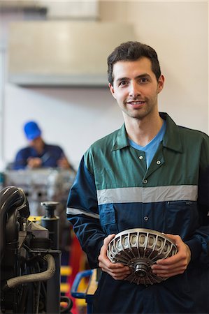 Happy instructor holding machine part in workshop Stock Photo - Premium Royalty-Free, Code: 6109-07497960