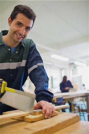 simsearch:6109-07497982,k - Smiling carpenter sawing wood in workshop Foto de stock - Sin royalties Premium, Código: 6109-07497976