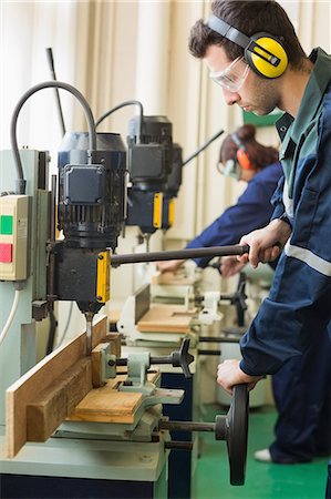 Craftsman with safety glasses drilling a piece of wood in workshop Stock Photo - Premium Royalty-Free, Code: 6109-07497984