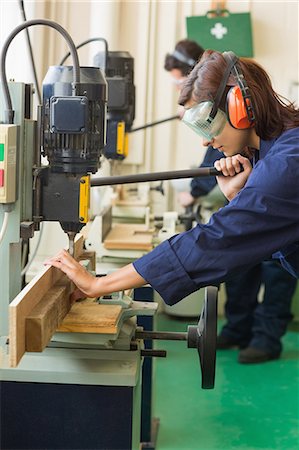 simsearch:6109-07497984,k - Trainee with safety glasses drilling a piece of wood in workshop Foto de stock - Sin royalties Premium, Código: 6109-07497986