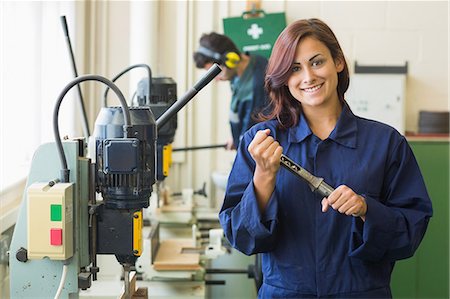 Smiling trainee showing tool in workshop Photographie de stock - Premium Libres de Droits, Code: 6109-07497991