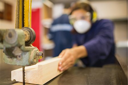 Trainee wearing safety protection using a saw in workshop Stock Photo - Premium Royalty-Free, Code: 6109-07497995