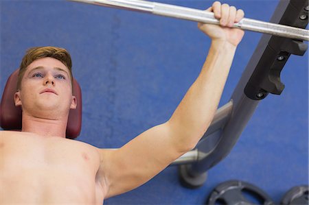 Muscular man lifting barbell lying on bench in weights room of gym Photographie de stock - Premium Libres de Droits, Code: 6109-07497900