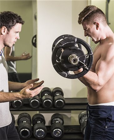 simsearch:400-07333355,k - Instructor correcting muscular determined man lifting barbell in weights room of gym Stock Photo - Premium Royalty-Free, Code: 6109-07497917