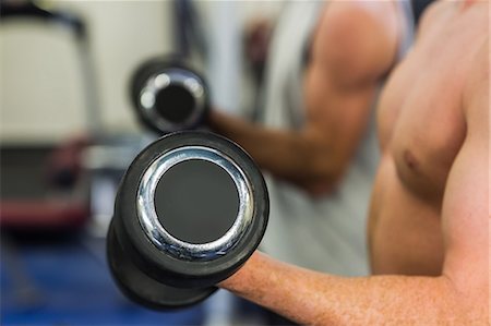 simsearch:6109-07497869,k - Two muscular men lifting dumbbells in weights room of gym Foto de stock - Sin royalties Premium, Código: 6109-07497923