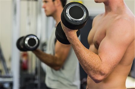 simsearch:6109-07497947,k - Two men lifting dumbbells in weights room of gym Foto de stock - Sin royalties Premium, Código: 6109-07497922