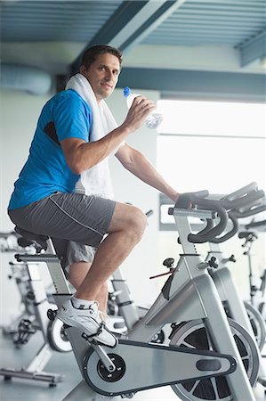 Side view portrait of a tired young man with water bottle working out at spinning class in gym Stock Photo - Premium Royalty-Free, Code: 6109-07498043