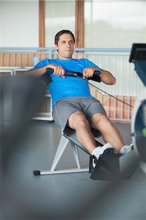 simsearch:6109-07498043,k - Full length of a determined young man working out on row machine in fitness studio Foto de stock - Sin royalties Premium, Código: 6109-07498050