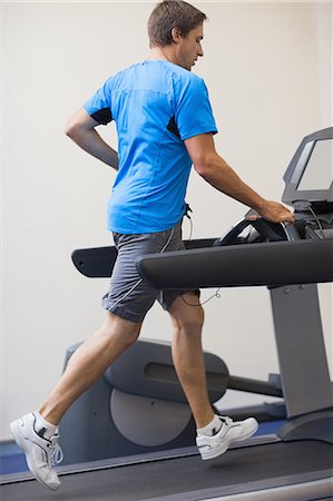 simsearch:614-05650886,k - Full length side view of a young healthy man running on treadmill at fitness studio Foto de stock - Sin royalties Premium, Código: 6109-07498057