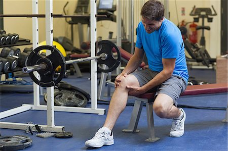 douleur - Full length of a healthy young man with an injured leg sitting in the gym Photographie de stock - Premium Libres de Droits, Code: 6109-07498065