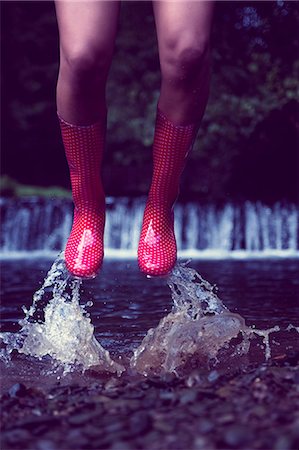 Close up low section of a woman in red gumboots jumping in water Foto de stock - Sin royalties Premium, Código: 6109-07498076