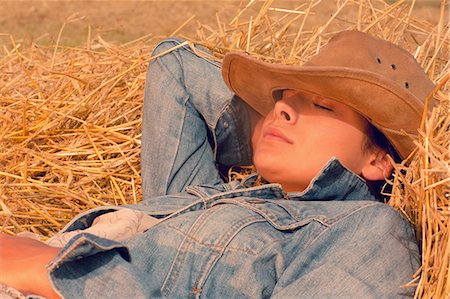 simsearch:6109-07498101,k - Beautiful young woman in hat relaxing on hay with eyes closed in summer Foto de stock - Sin royalties Premium, Código: 6109-07498096