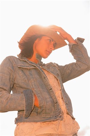 simsearch:6109-07498101,k - Low angle view of a young woman in hat against the sunny sky Foto de stock - Sin royalties Premium, Código: 6109-07498098
