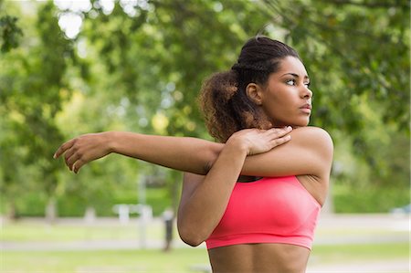 Serious healthy young woman stretching her hand during exercise at the park Stock Photo - Premium Royalty-Free, Code: 6109-07498030