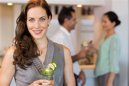 party cocktails - Smiling woman holding cocktail glass with friends at the bar Stock Photo - Premium Royalty-Free, Code: 6109-07600945