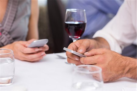 Mid section of a couple with wine glass text messaging Stock Photo - Premium Royalty-Free, Code: 6109-07600963