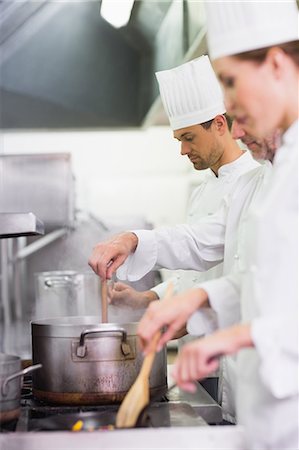 simsearch:6109-08489839,k - Team of chefs cooking at the stove Foto de stock - Sin royalties Premium, Código: 6109-07601054