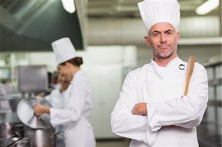 relate (co-workers) - Head chef looking at camera holding wooden spoon Stock Photo - Premium Royalty-Free, Code: 6109-07601063