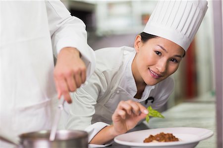 Happy chef putting basil leaf on spaghetti dish Stock Photo - Premium Royalty-Free, Code: 6109-07601081