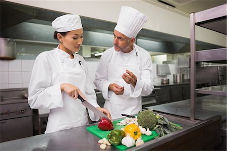 simsearch:6113-06626533,k - Chef teaching trainee how to slice vegetables Stock Photo - Premium Royalty-Free, Code: 6109-07601082