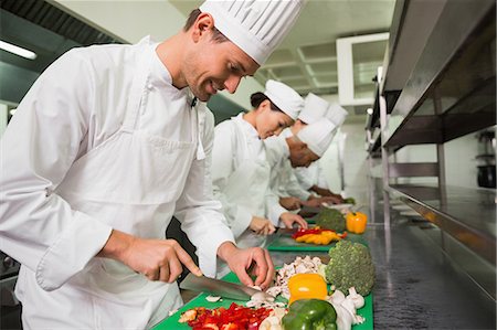 simsearch:6109-07601106,k - Row of trainee chefs slicing vegetables Stock Photo - Premium Royalty-Free, Code: 6109-07601087