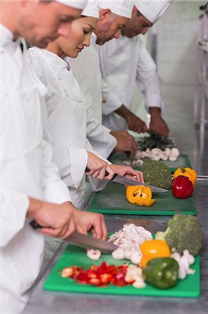 simsearch:6109-07601106,k - Row of trainee chefs slicing vegetables Stock Photo - Premium Royalty-Free, Code: 6109-07601084