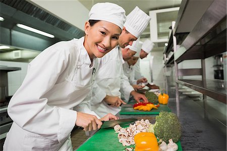 slicing vegetables - Row of trainee chefs slicing vegetables Stock Photo - Premium Royalty-Free, Code: 6109-07601086