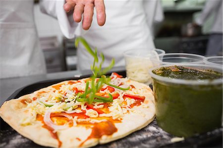 simsearch:6109-07601151,k - Chef sprinkling pepper on a pizza Stockbilder - Premium RF Lizenzfrei, Bildnummer: 6109-07601096