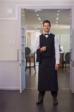 simsearch:6109-07601192,k - Handsome waiter smiling at camera Foto de stock - Sin royalties Premium, Código: 6109-07601178